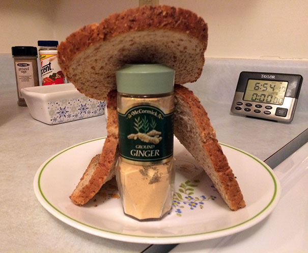 Funniest dads create a gingerbread house using a ginger bottle and bread slices on a kitchen counter.