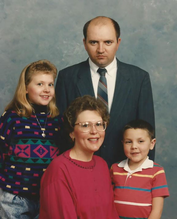 Funny dad with serious expression in a retro family photo, surrounded by his smiling family members.
