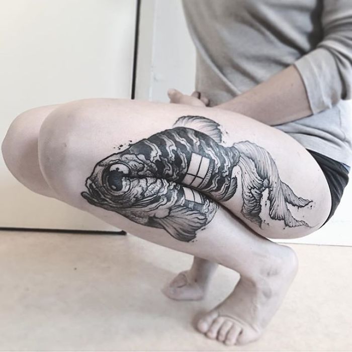 Fish tattoo on a person's bent leg, showcasing its full design when extended. Fish tattoo on a person's bent leg, showcasing its full design when extended.
