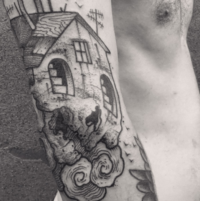 Tattoo art on an arm featuring a house and swirling clouds, visible when limbs are extended. Tattoo art on an arm featuring a house and swirling clouds, visible when limbs are extended.