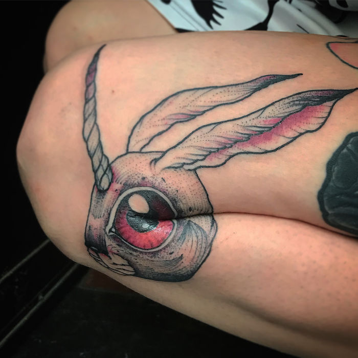 Unique leg tattoo of a rabbit's head with a unicorn horn, designed to reveal more detail when the leg is extended. Unique leg tattoo of a rabbit's head with a unicorn horn, designed to reveal more detail when the leg is extended.