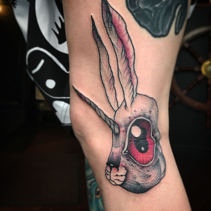 Tattoo transforms on leg extension, revealing a unique rabbit design with a horn and large pink eye.