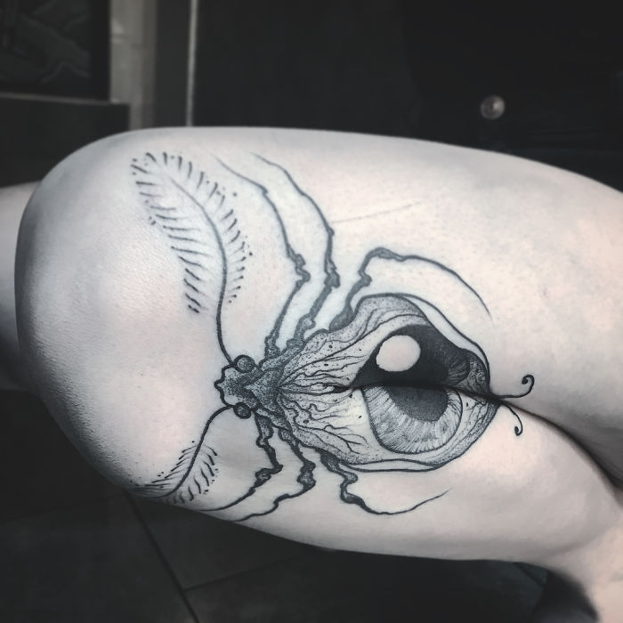 Tattoo of a detailed eye design on a person's leg, revealing intricate artwork when the leg is extended. Tattoo of a detailed eye design on a person's leg, revealing intricate artwork when the leg is extended.