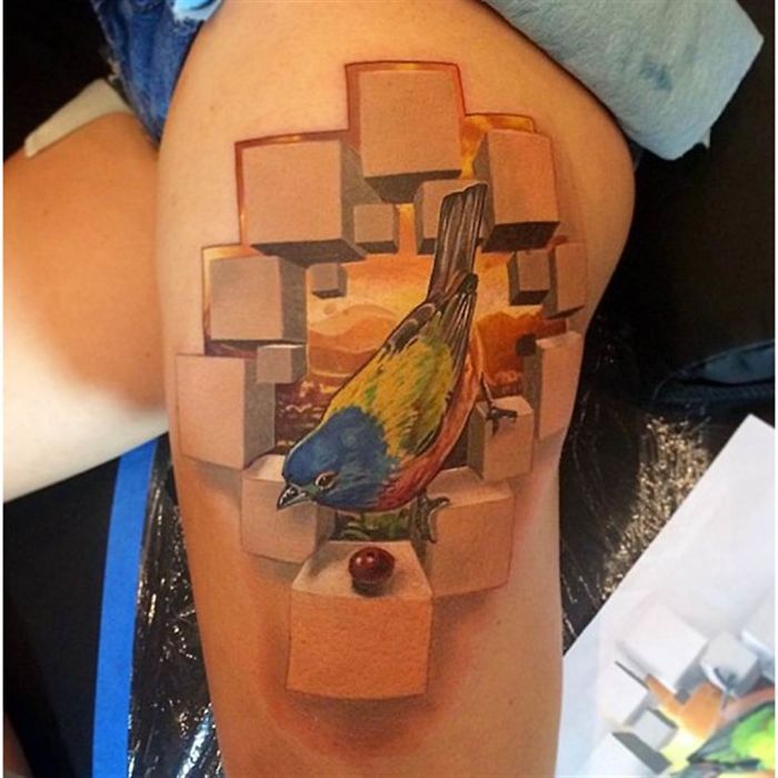 3D tattoo of a colorful bird and cubes, creating a realistic optical illusion on the skin.