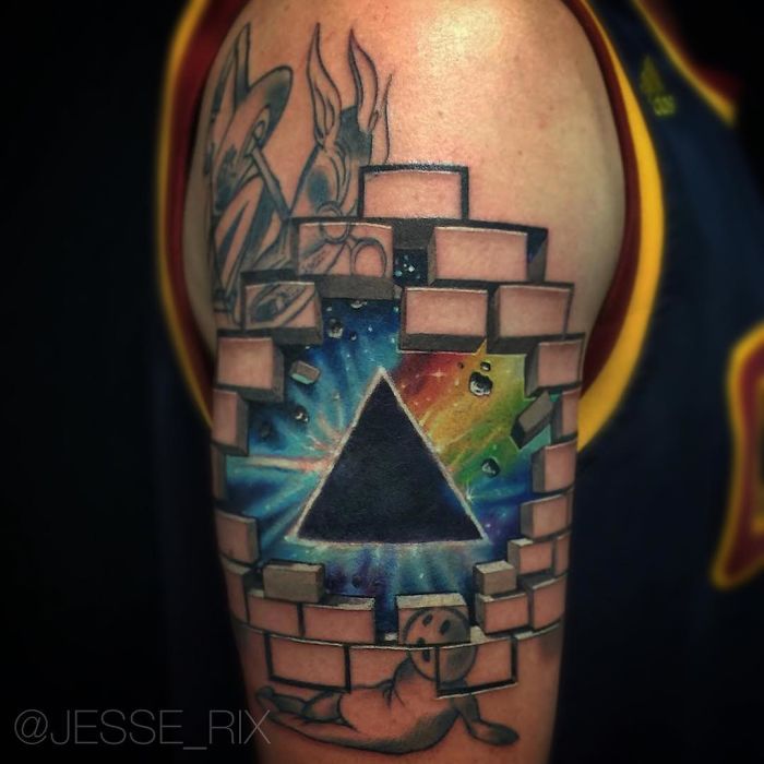 3D tattoo of a pyramid breaking through bricks on an arm, featuring vibrant colors and detailed design.