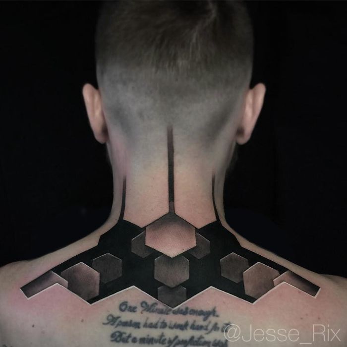 3D tattoo on back with geometric design and text, appearing three-dimensional.