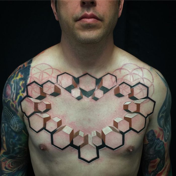 3D tattoos of geometric cubes on a man's chest create an optical illusion effect.