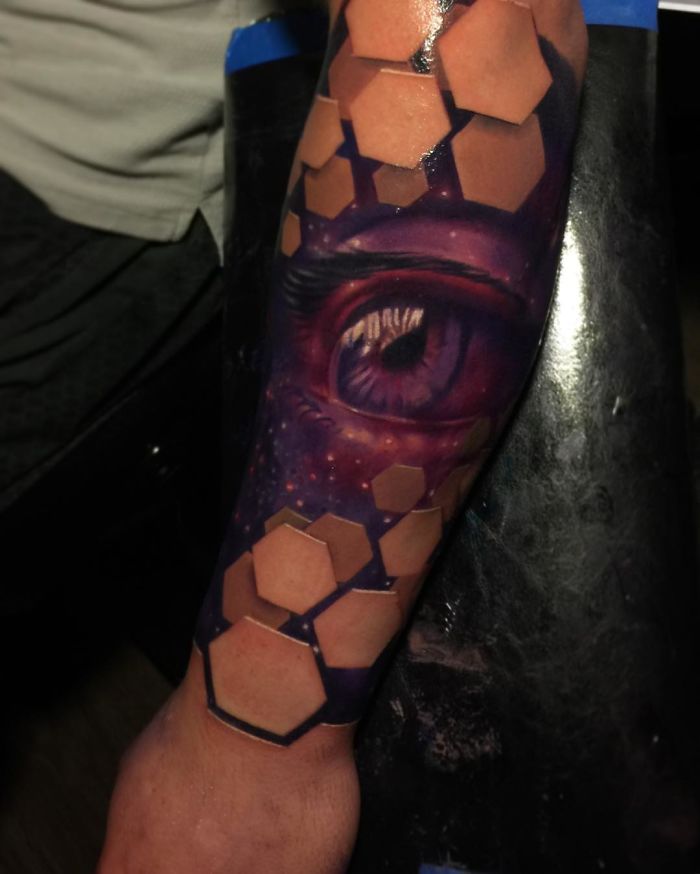 3D tattoo of a realistic eye with geometric shapes on an arm.
