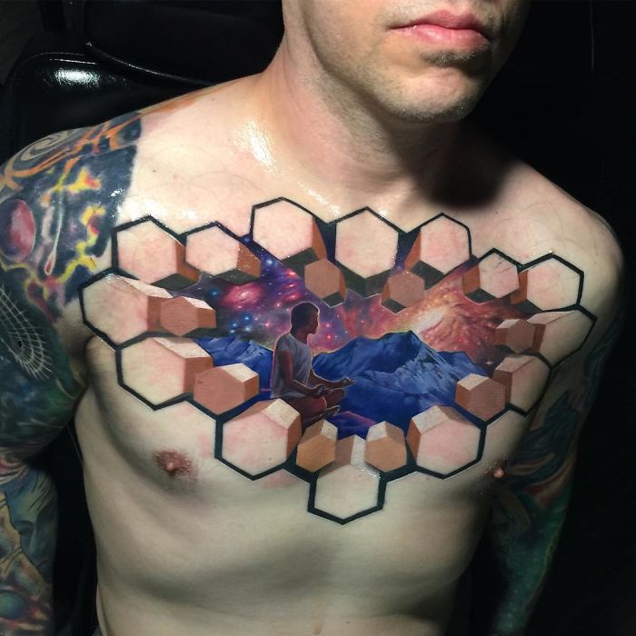 3D tattoo on chest featuring geometric pattern with nature and space elements, creating an optical illusion.