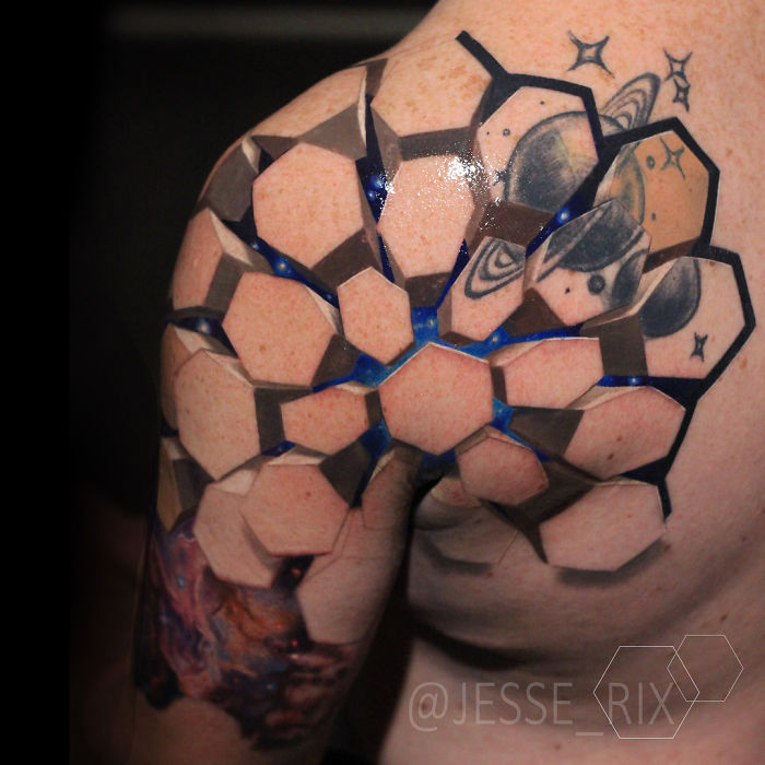 3D tattoo on shoulder featuring hexagonal shapes and cosmic elements, creating an optical illusion.