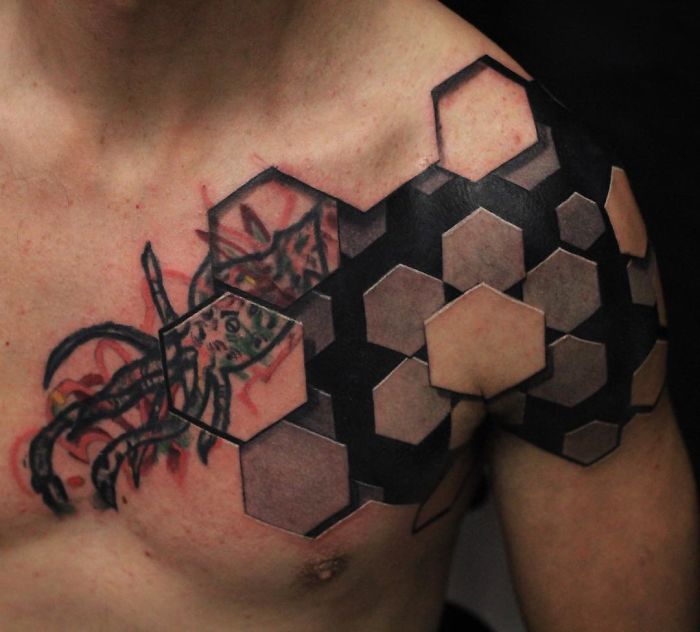 3D tattoo of hexagons on a man's shoulder and chest, creating an amazing optical illusion.