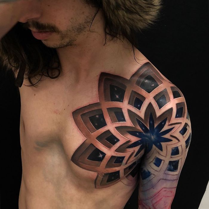 3D tattoo on a person's shoulder with intricate geometric patterns in blue and black, creating a stunning optical illusion.
