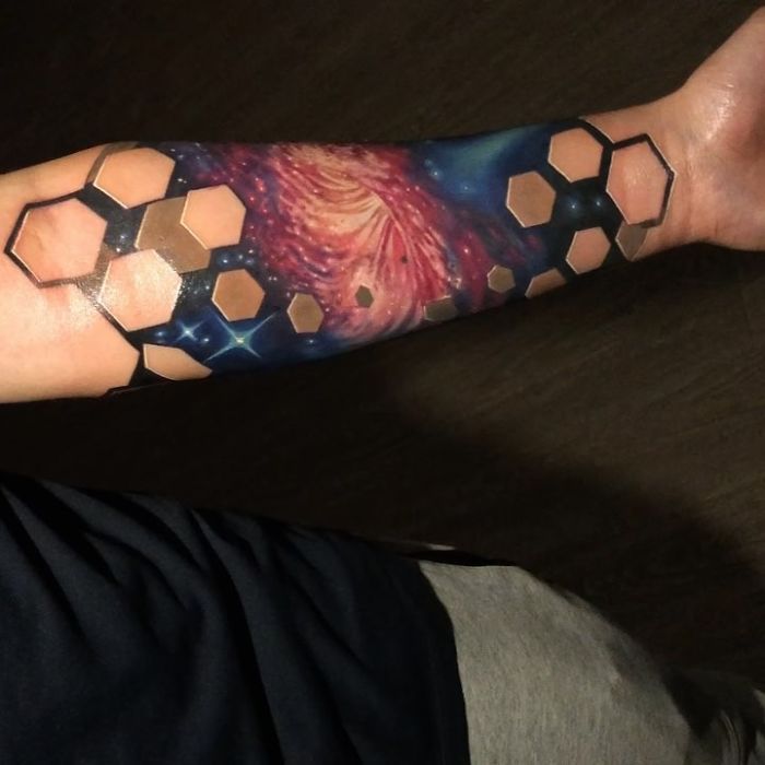 3D tattoo on forearm with hexagonal patterns and galaxy theme, showcasing realistic artistry.