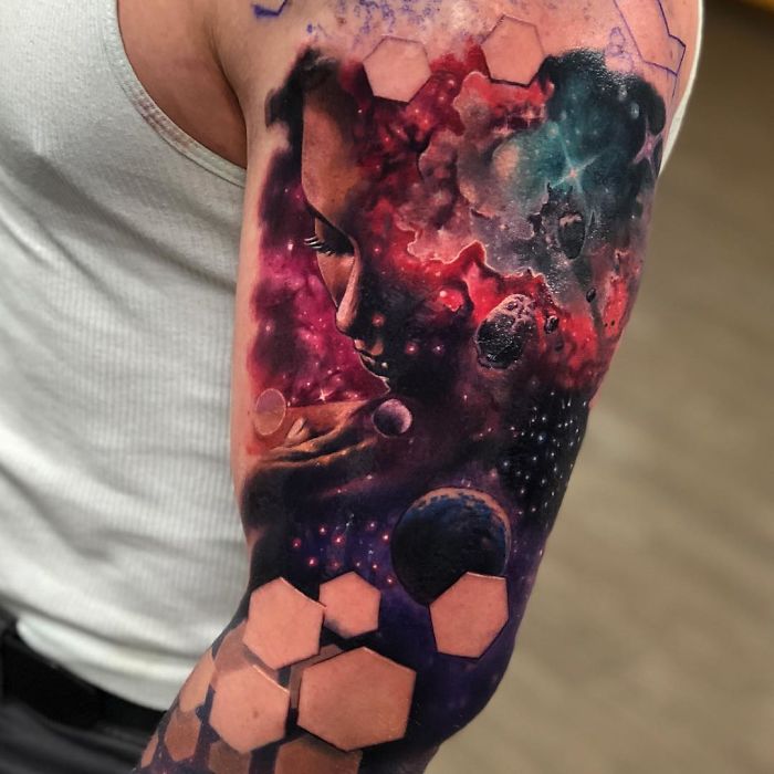 3D tattoo of a cosmic scene with a woman's face, blending galaxies and geometric shapes on an arm.