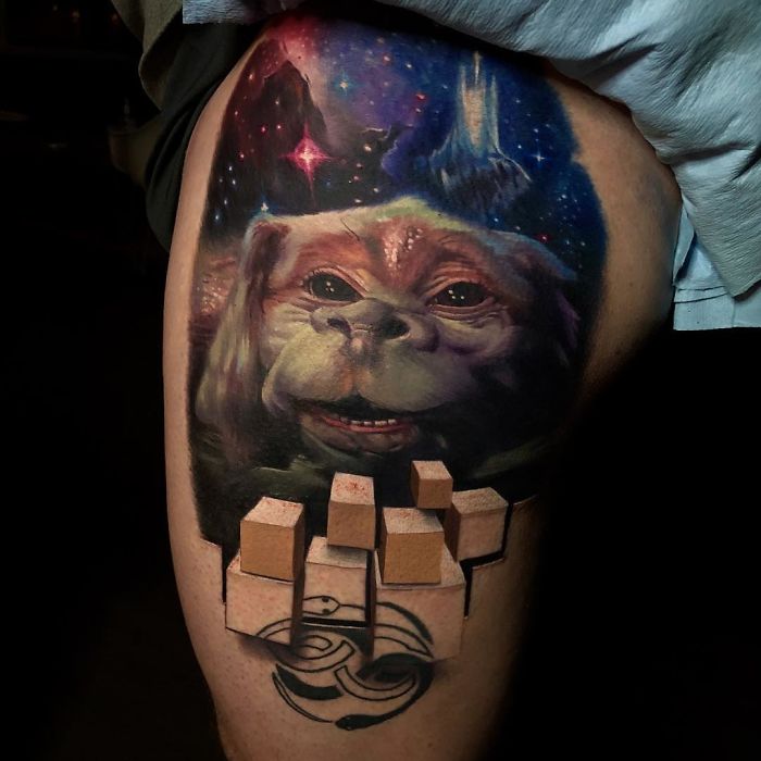 3D tattoo of a fantasy creature and geometric cubes on a person's thigh, showing intricate artistic detail.