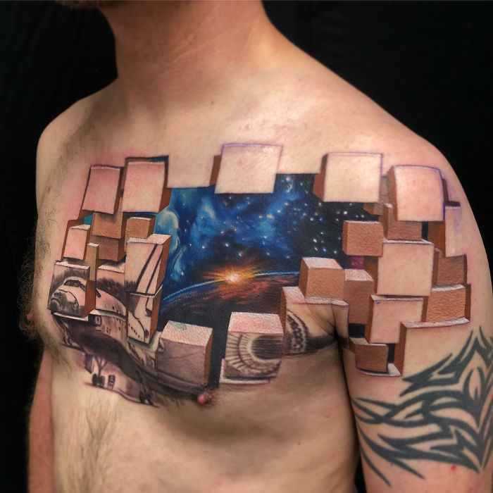 3D tattoo of a space scene and bricks on a man's chest, using perspective to create an optical illusion.