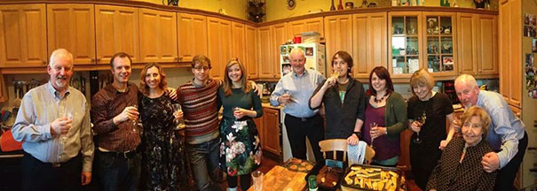 Group of people in a cozy kitchen raising glasses, capturing the essence of funny dads in a family gathering.
