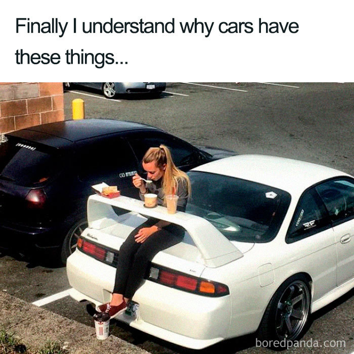 Woman using car spoiler as a table for food in a parking lot, creating a funny food meme.