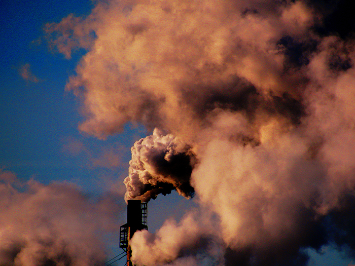Thick smoke rising from industrial chimney under blue sky, illustrating environmental impact near Antarctica facts.