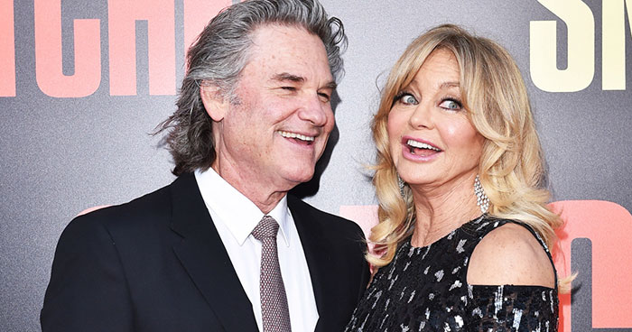 Two celebrities smiling together at a red carpet event, showcasing couples who fell in love while acting together.