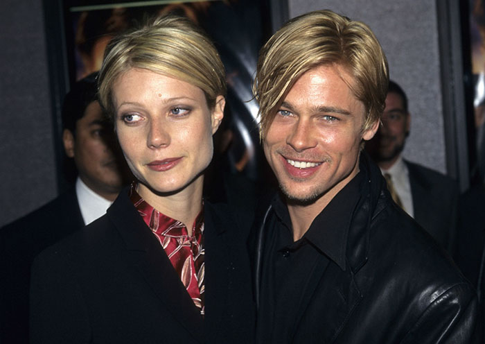 Gwyneth Paltrow and Brad Pitt smiling together at an event, showcasing celebrities who fell in love while acting.