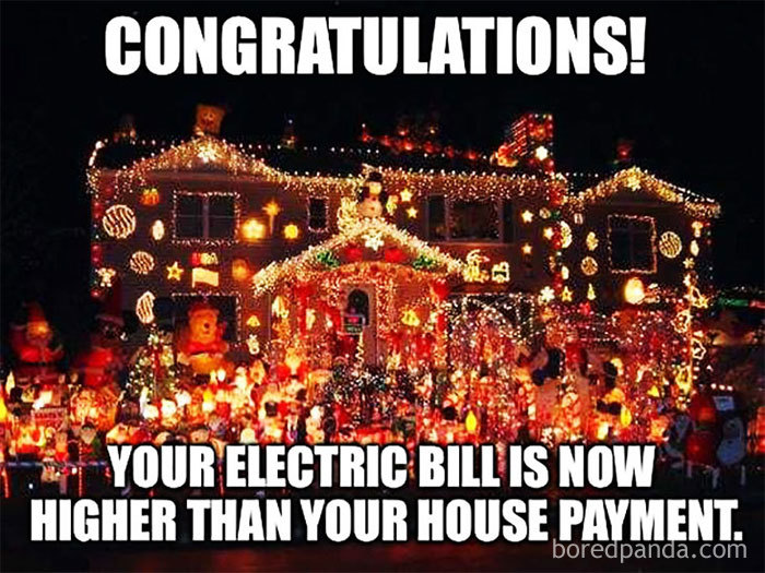 House covered in Christmas lights with funny text about high electric bills.