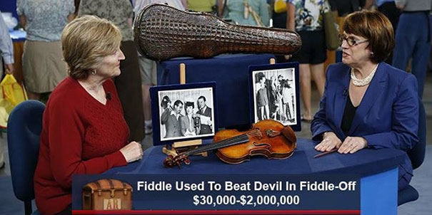 Two women at Antiques Roadshow with a violin, humorous caption about a fiddle-off with the devil, valued at $30,000-$2,000,000.