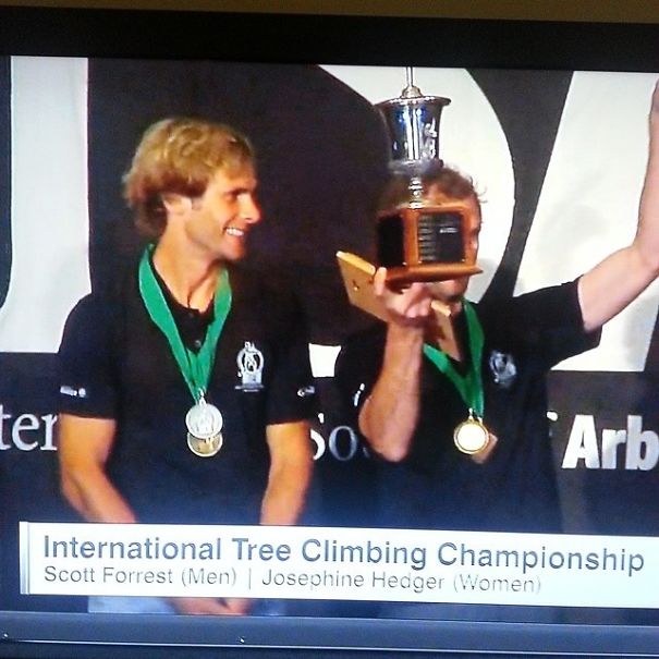 Winners at International Tree Climbing Championship show off medals and trophy, highlighting their dedication to the job.