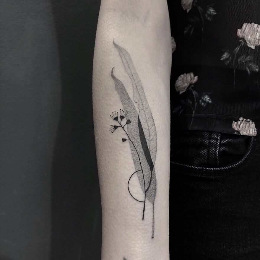 Minimalist tattoo featuring botanical elements on a person's arm.