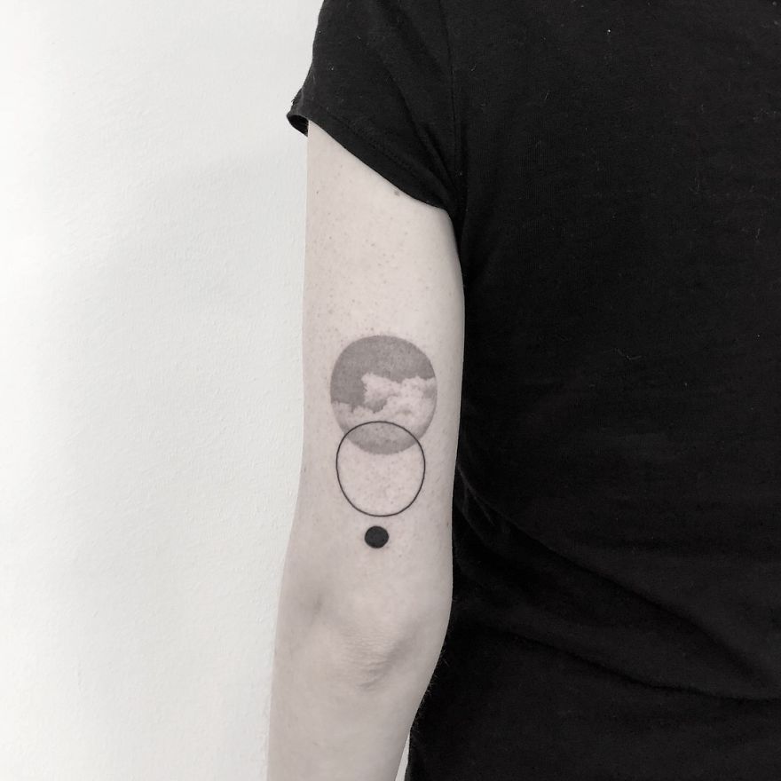 Minimalist tattoo on arm featuring botanical design with geometric elements.