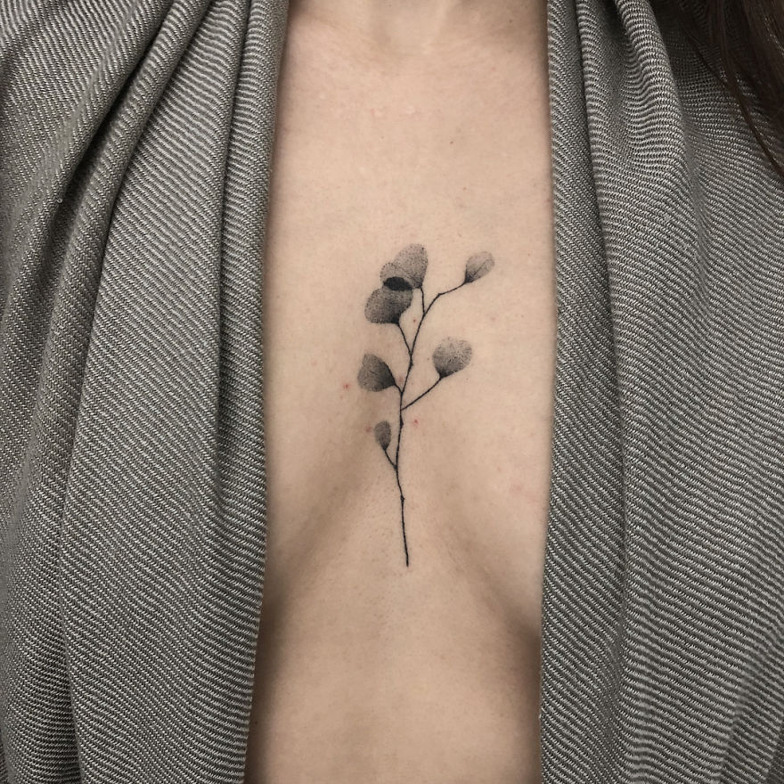 Minimalist botanical tattoo design on chest, featuring delicate, thin black lines with soft leaf details.