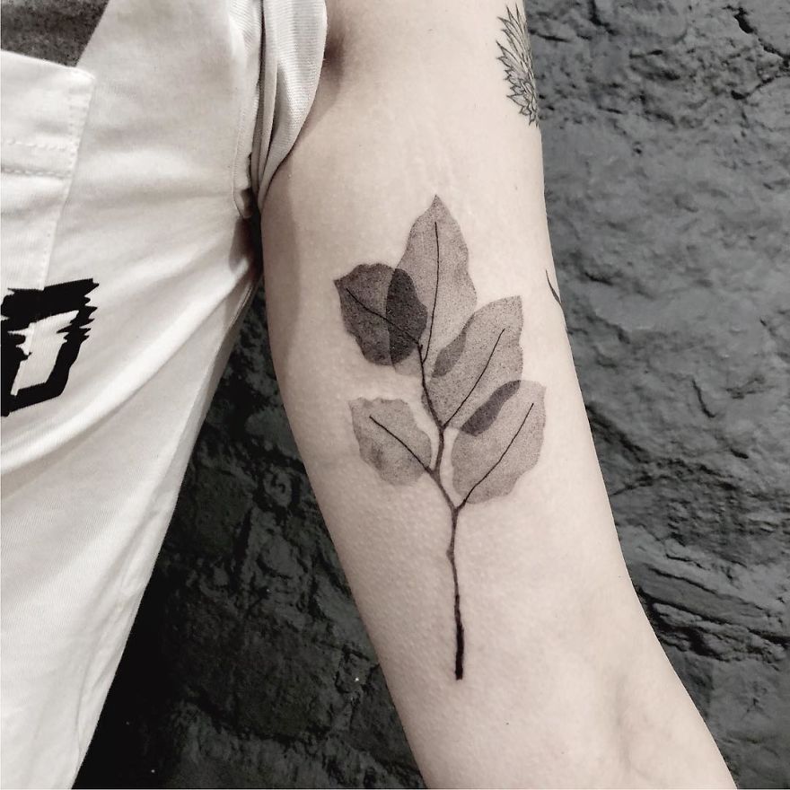 Minimalist botanical tattoo of leaves on an arm, showcasing clean lines and nature-inspired design.