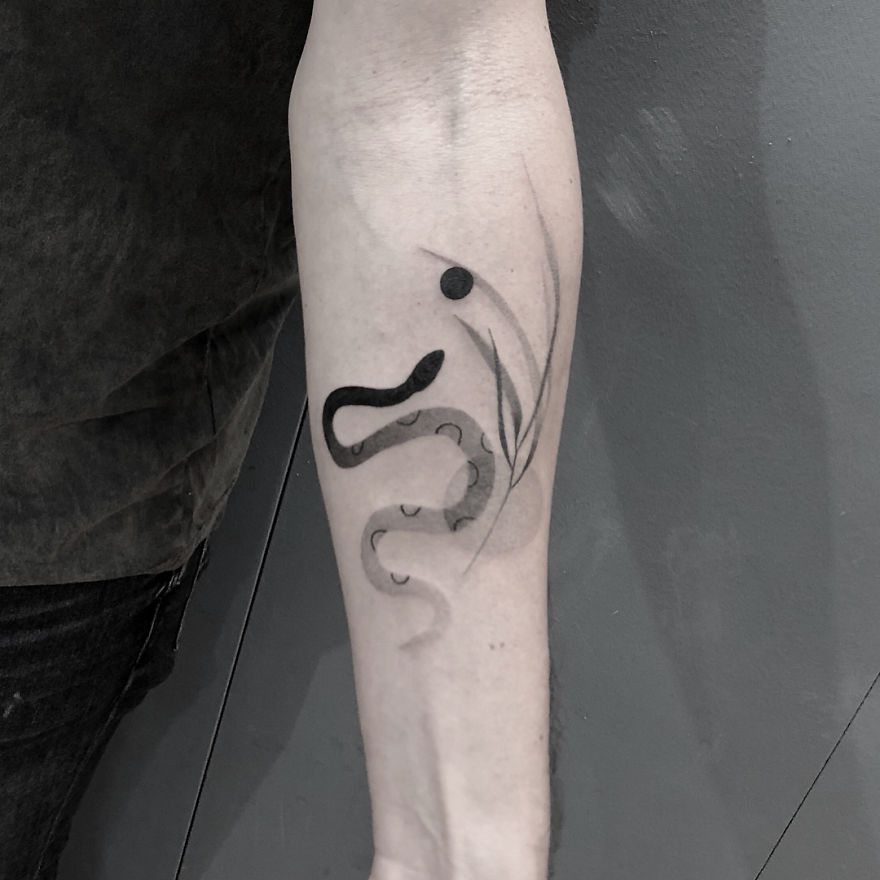 Minimalist tattoo on forearm featuring abstract botanical illustrations.