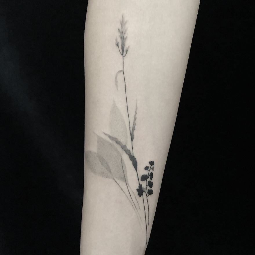 Minimal botanical tattoo design on forearm, featuring simple floral elements with delicate linework.