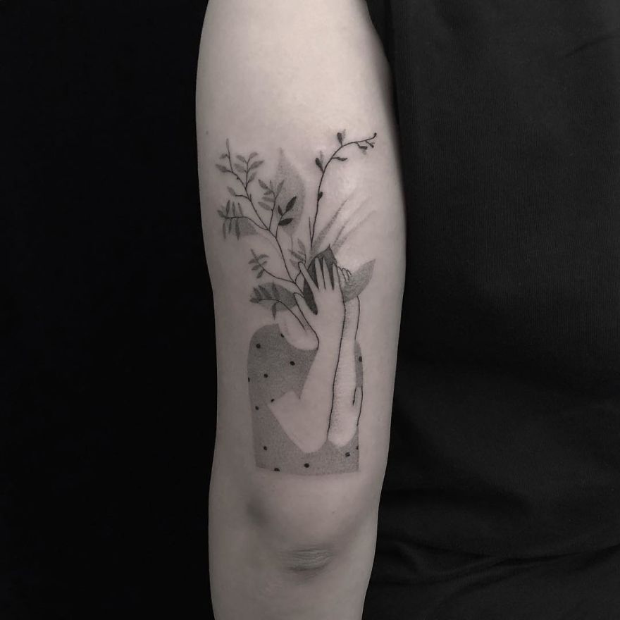 Minimalist tattoo with botanical illustration on a person's arm in a monochrome design.