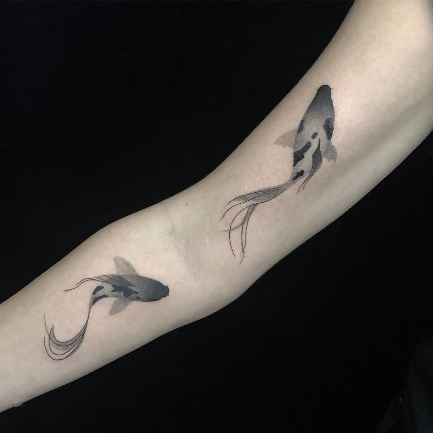 Minimalist botanical-inspired tattoo of koi fish on an arm.