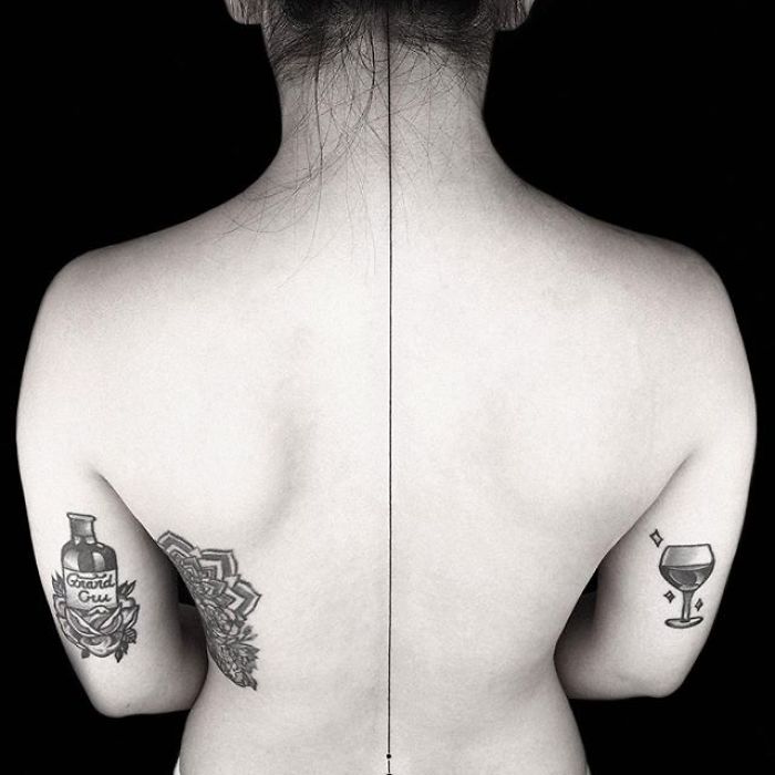 Back view with geometric tattoos by Turkish artist Okan Uçkun, featuring symmetrical designs on both shoulders.