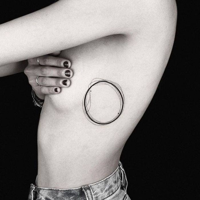 Geometric tattoo by Turkish artist Okan Uçkun, featuring overlapping circles on the side of a person's chest.