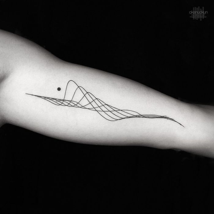 Geometric tattoo by Turkish artist Okan Uçkun, featuring intricate lines and dot design on forearm.