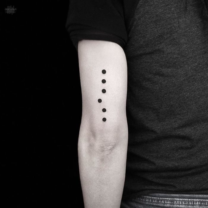 Geometric tattoo of five black dots on a person's arm by Turkish artist Okan Uçkun.