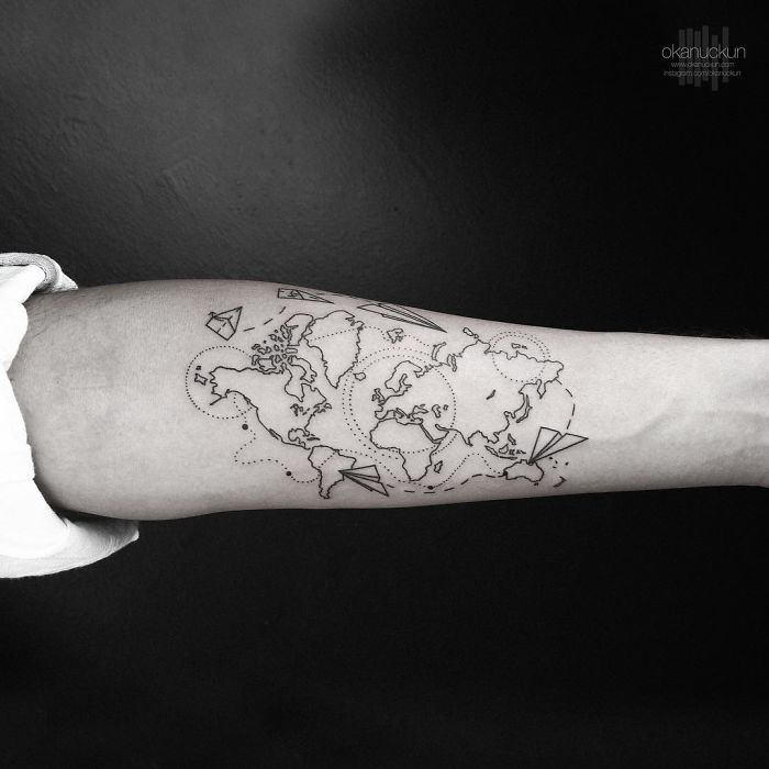 Geometric tattoo of a world map with paper planes by Turkish artist Okan Uçkun on forearm.