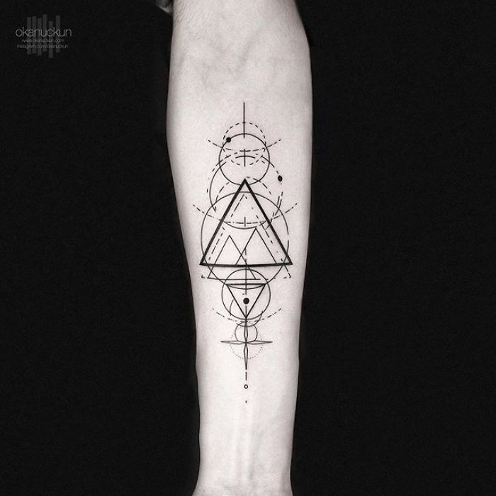 Geometric tattoo by Turkish artist Okan Uçkun featuring intricate circles and triangles on a forearm.
