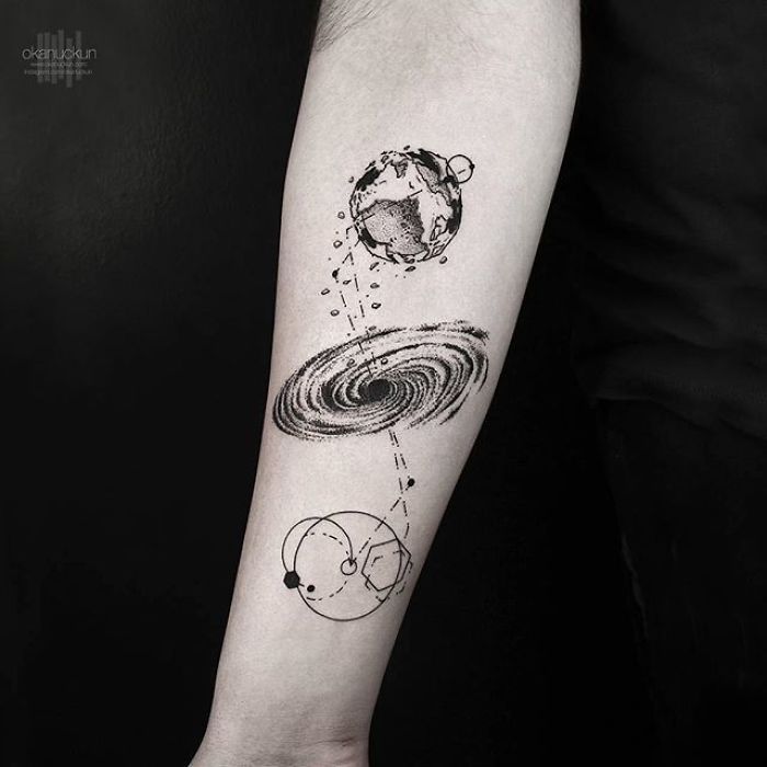 Geometric tattoo design by Turkish artist Okan Uçkun on forearm, featuring planets and a galaxy motif.