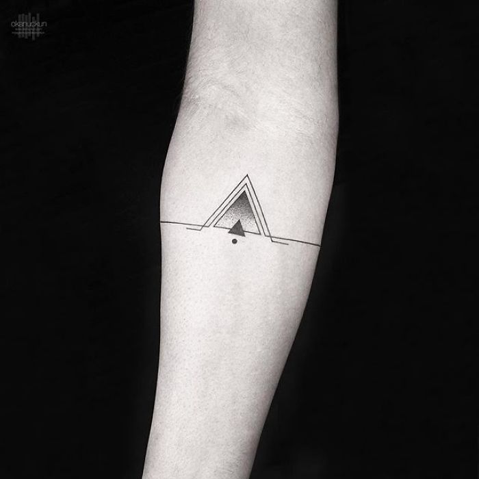 Geometric tattoo with triangle design by Turkish artist Okan Uçkun on a forearm.