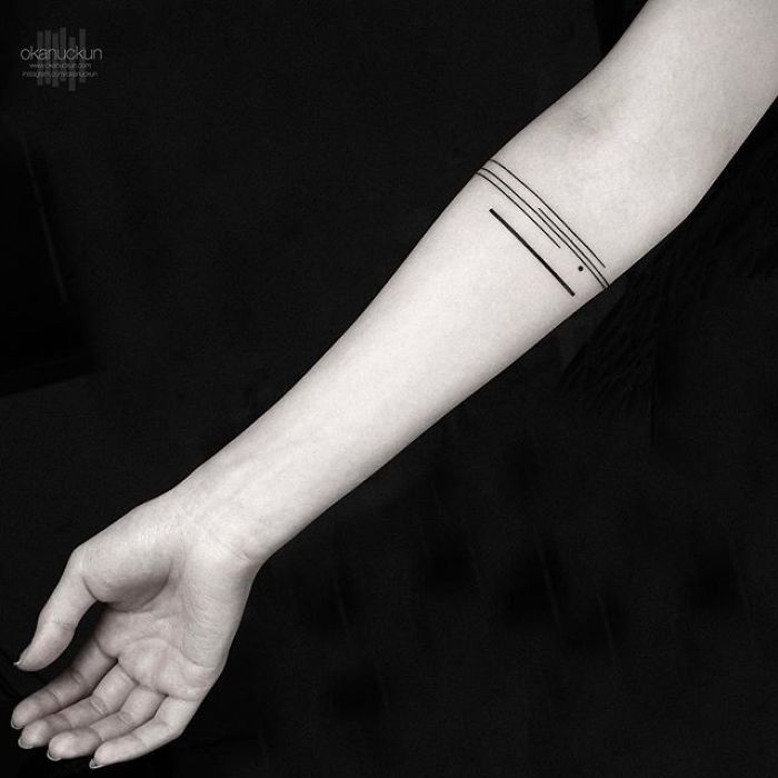 Minimalist geometric tattoo on forearm featuring fine lines by Turkish artist Okan Uçkun.