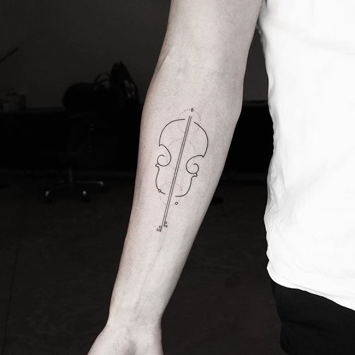 Geometric tattoo of a violin on a person's forearm by Turkish artist Okan Uçkun.