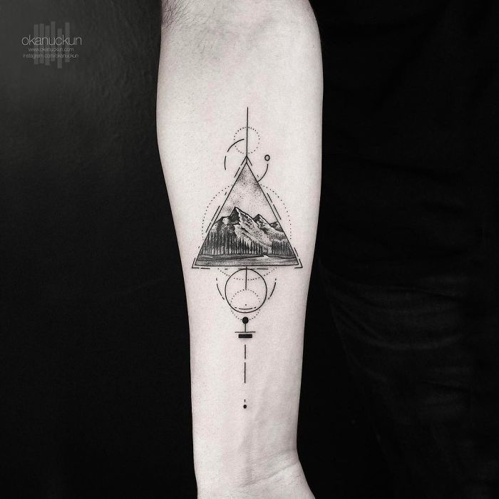Geometric tattoo by Turkish artist Okan Uçkun, featuring a mountain within a triangle and circular elements on arm.