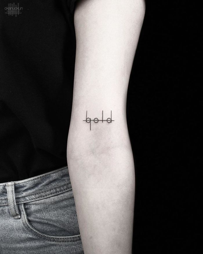 Geometric tattoo by Turkish artist Okan Uçkun on forearm, featuring a minimalistic design with the word "bold".