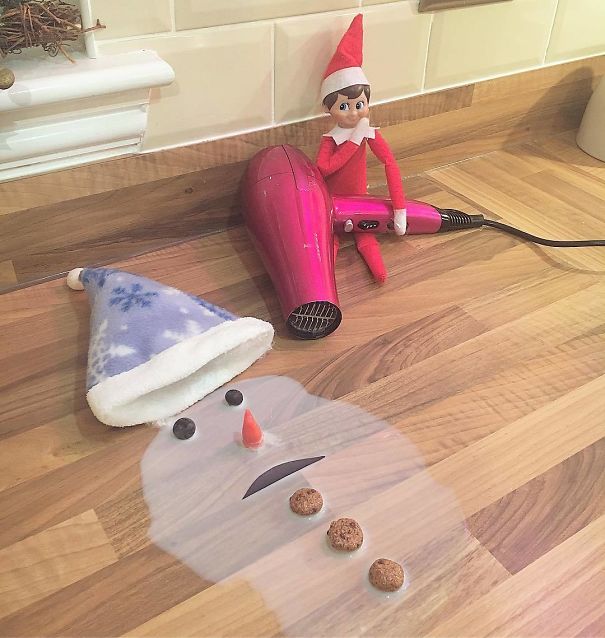 "Elf On The Shelf idea with the elf holding a hairdryer next to a melted snowman scene, complete with hat, carrot nose, and buttons."