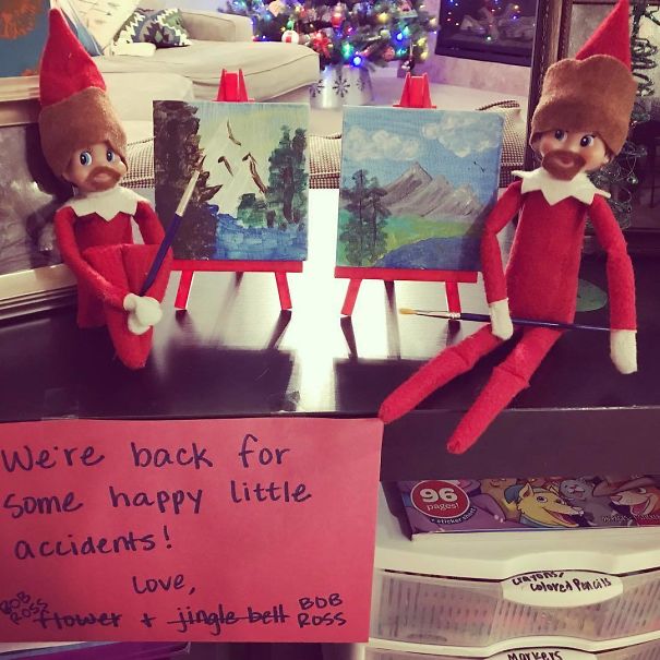 "Elf On The Shelf idea with two elves dressed as 'Bob Ross,' painting miniature landscapes with a sign saying 'We're back for some happy little accidents!'"